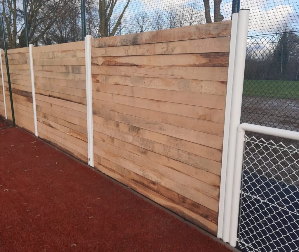 Panneau de protection en bois le long d'un terrain de sport.